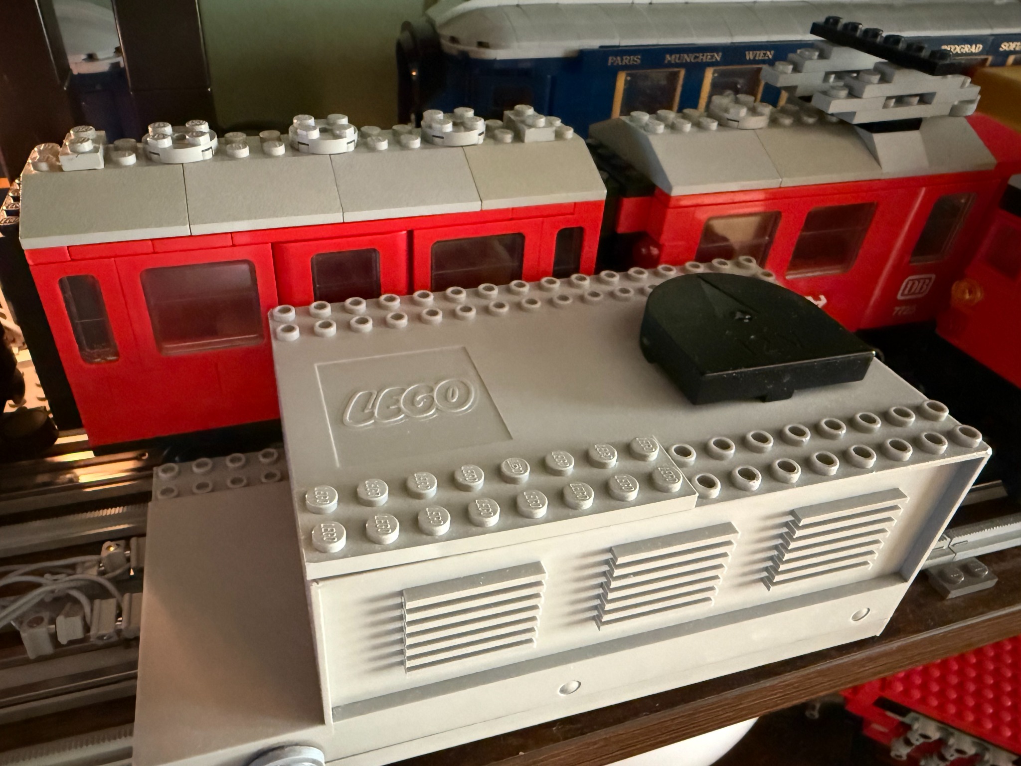 Dettaglio del trasformatore LEGO 12 V accanto a un treno rosso della Grey Era